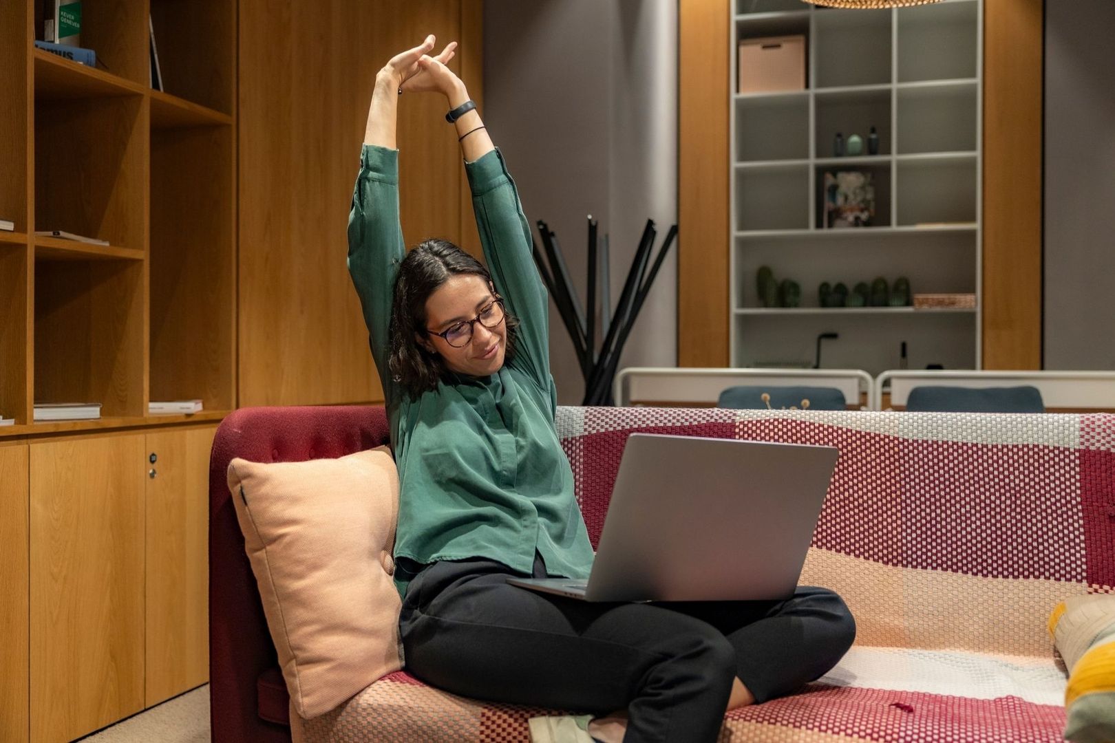 Person sitter med laptop och sträcker armarna över huvudet
