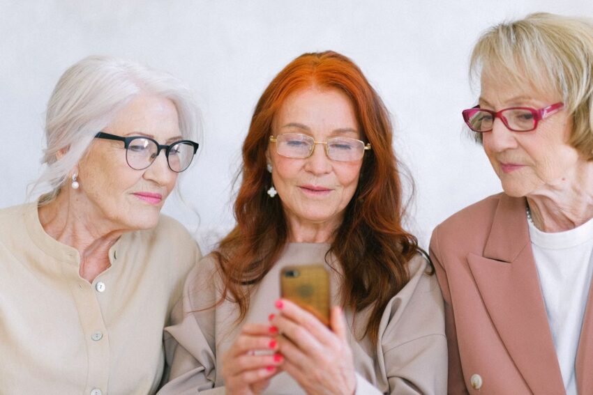 Tre äldre kvinnor tittar på en smartphone tillsammans